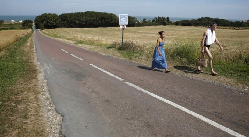 A couple walk inland from the former D-Day landing zone of Gold Beach in Ver-sur-Mer