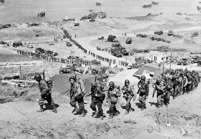 Handout photo of U.S. Army reinforcements marching up a hill past a German bunker after the D-Day landings near Colleville sur Mer