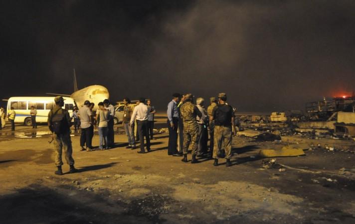 Smoke bellows as security officials and airport staff visit the site damaged by Sunday's Taliban attack on Jinnah International Airport in Karachi