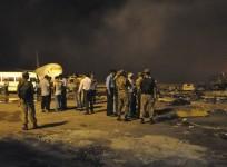 Smoke bellows as security officials and airport staff visit the site damaged by Sunday's Taliban attack on Jinnah International Airport in Karachi