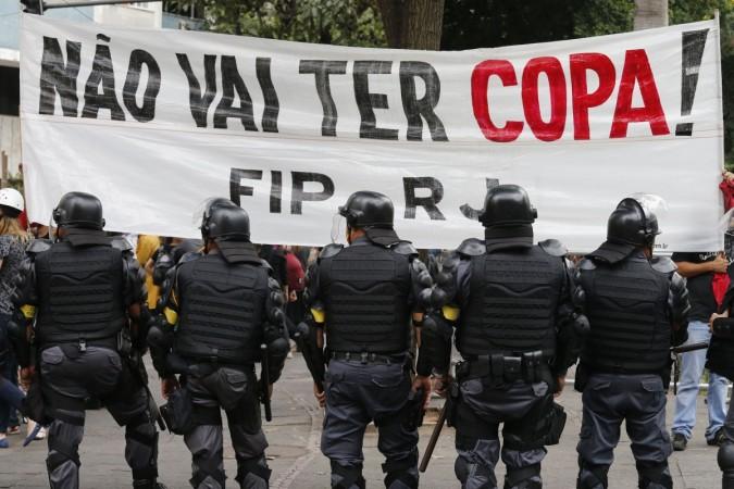 Police officers stand guard in front of a banner during a protest against the 2014 World Cup in Rio de Janeiro