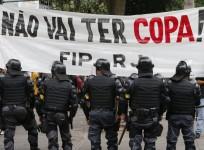 Police officers stand guard in front of a banner during a protest against the 2014 World Cup in Rio de Janeiro