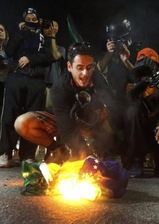 A demonstrator burns a Brazilian flag during a protest against the 2014 World Cup in Rio de Janeiro A demonstrator burns a Brazilian flag during a protest against the 2014 World Cup in Rio de Janeiro
