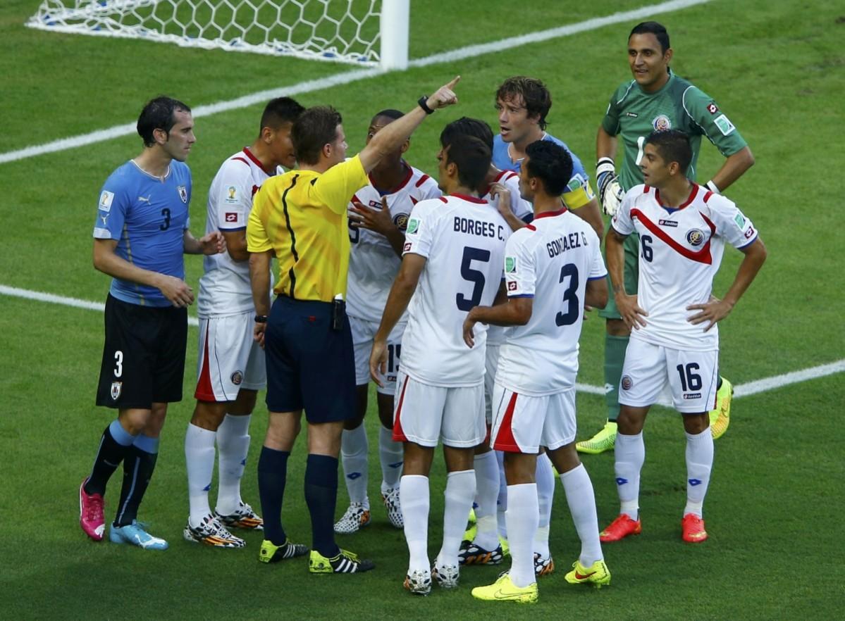 Costa Rica's national soccer players argue with referee Brych after he issued the team a penalty Uruguay v Costa Rica