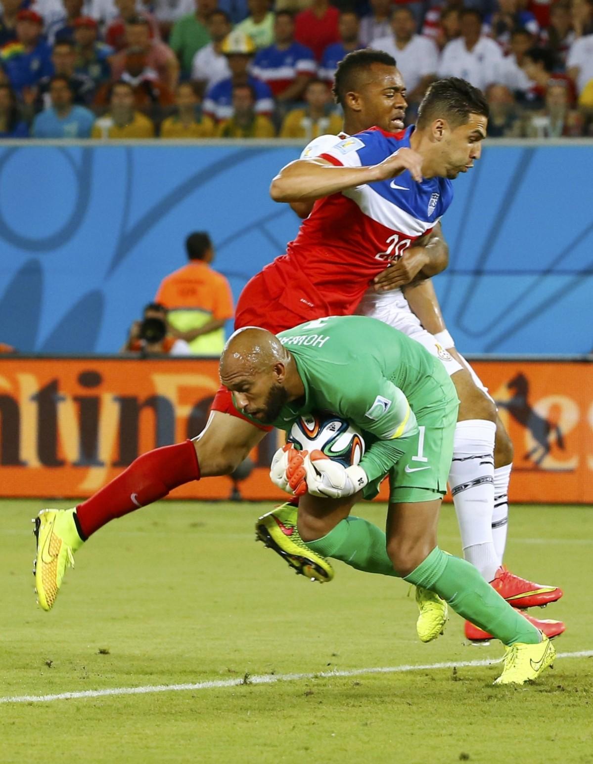 Cameron of the U.S. fights for the ball with Ghana's Ayew, while goalkeeper Howard of the U.S. makes a save, during World Cup Group G soccer match at Dunas arena Ghana vs USA