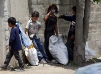Syrian refugee children collect plastics as they stand along a street in south of Sidon