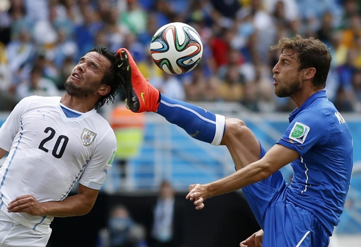 Uruguay's Alvaro Gonzalez jumps for the ball against Italy's Claudio Marchisio during their 2014 World Cup Group D match at the Dunas arena in Natal Italy vs Uruguay