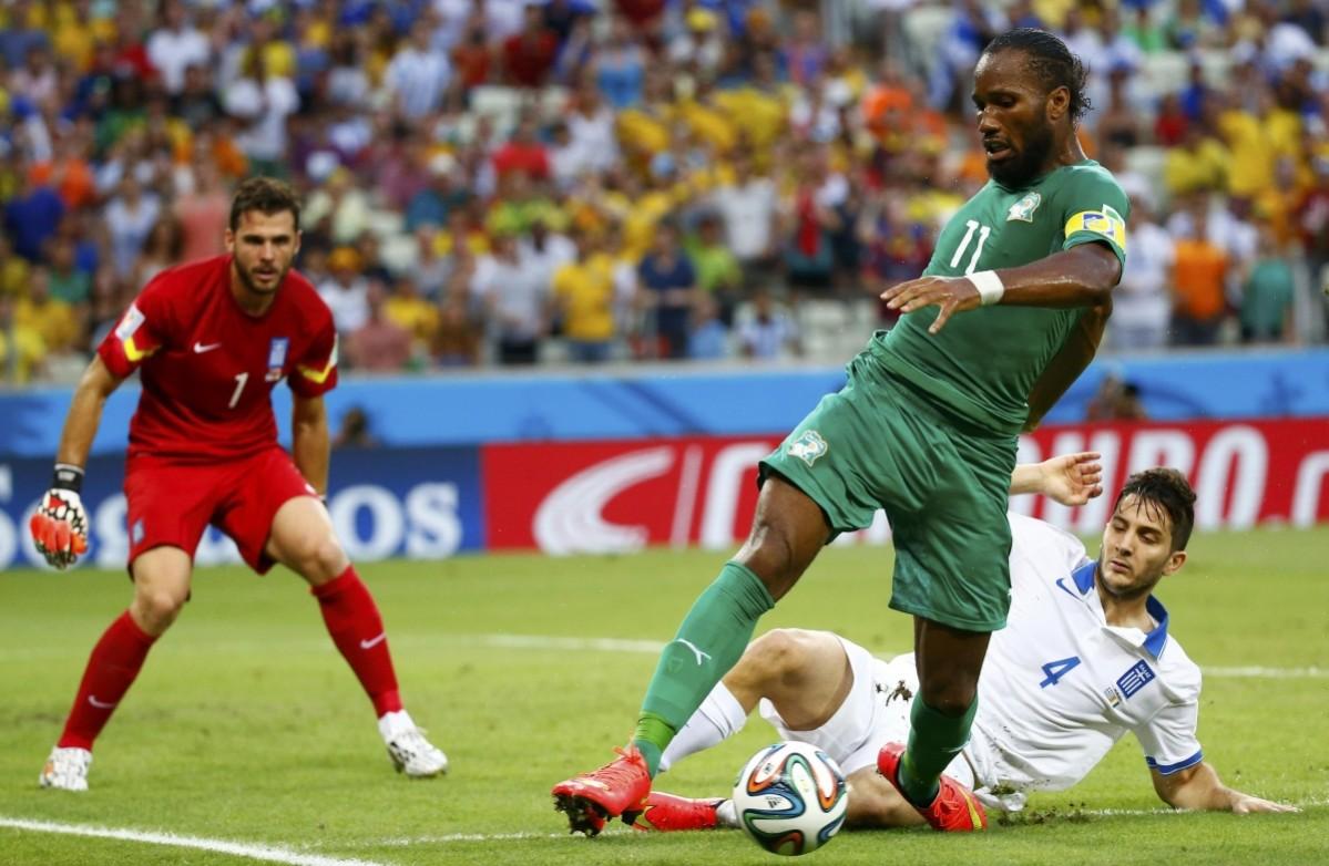 Ivory Coast's Drogba is challenged for the ball by Greece's Manolas in front of Greece's Karnezis during their 2014 World Cup Group C soccer match at the Castelao arena in Fortaleza Greece vs Ivory Coast