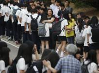 Relatives of the April 16 ferry disaster victims comfort students who survived the accident as they make their way back to school in Ansan