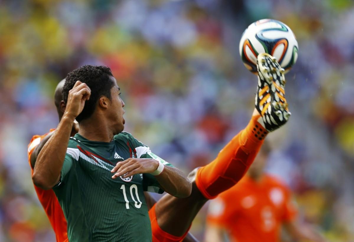Mexico's Dos Santos fights for the ball with Martins Indi of the Netherlands during their 2014 World Cup round of 16 game at the Castelao arena in Fortaleza Netherlands vs Mexico