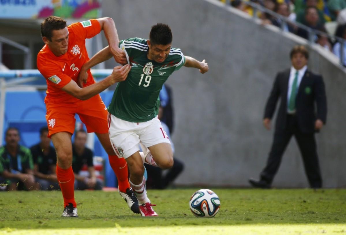 De Vrij of the Netherlands fights for the ball with Mexico's Peralta as Mexico's coach Herrera walks in the background during their 2014 World Cup round of 16 game at the Castelao arena in Fortaleza Netherlands vs Mexico