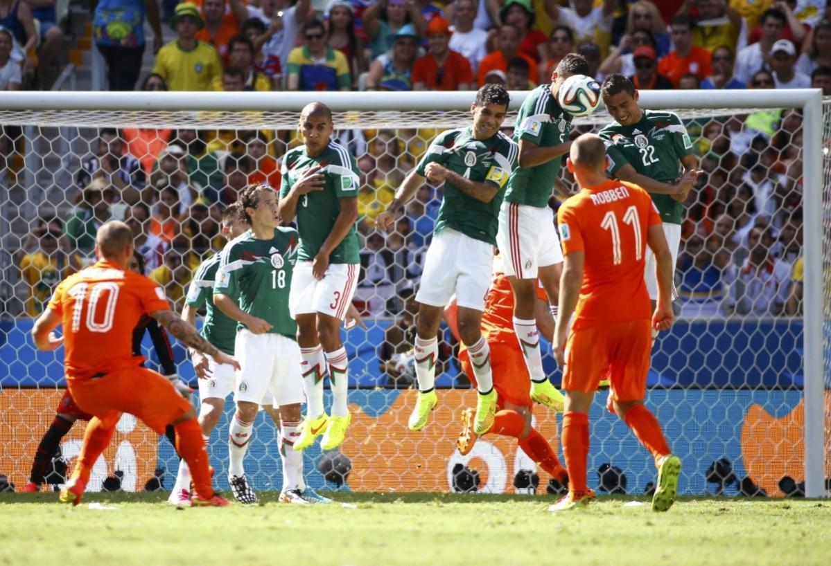 Sneijder of the Netherlands takes a free kick but is blocked by Mexico's national soccer players jumping to defend during their 2014 World Cup round of 16 game at the Castelao arena in Fortaleza Netherlands vs Mexico