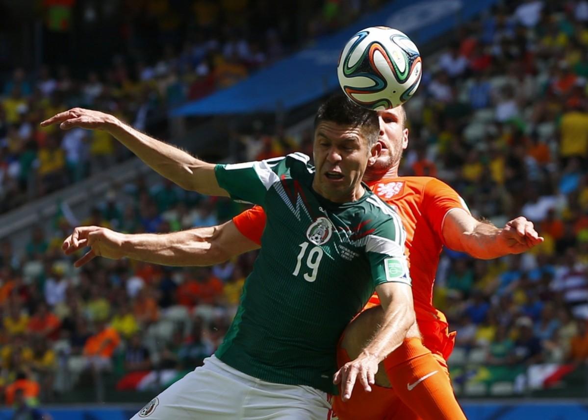 Ron Vlaar of the Netherlands fights for the ball against Mexico's Oribe Peralta during their 2014 World Cup round of 16 game at the Castelao arena in Fortaleza Netherlands v Chile