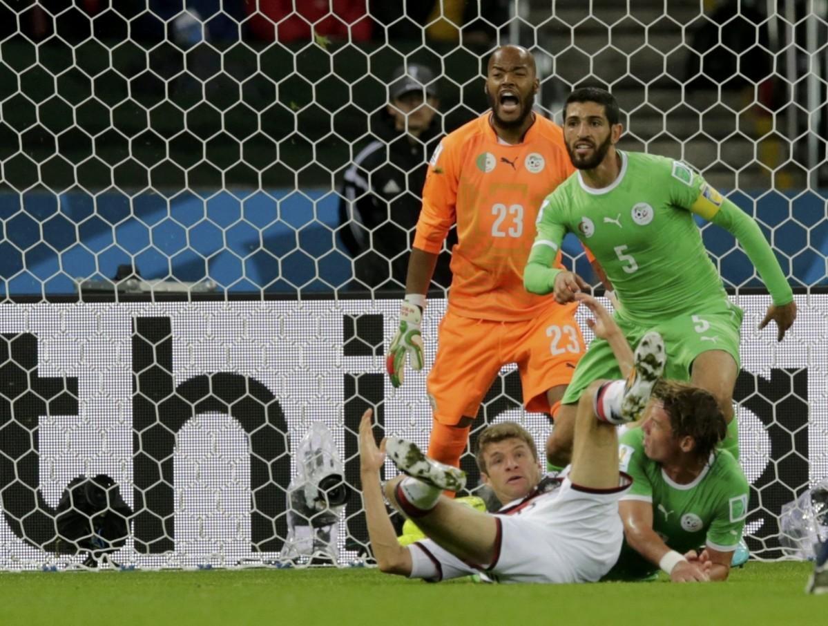 Germany's Thomas Mueller falls to the ground as Algeria's Rafik Halliche and Rais Mbolhi keep their eye on the ball during their 2014 World Cup round of 16 game at the Beira Rio stadium in Porto Alegre Germany vs Algeria