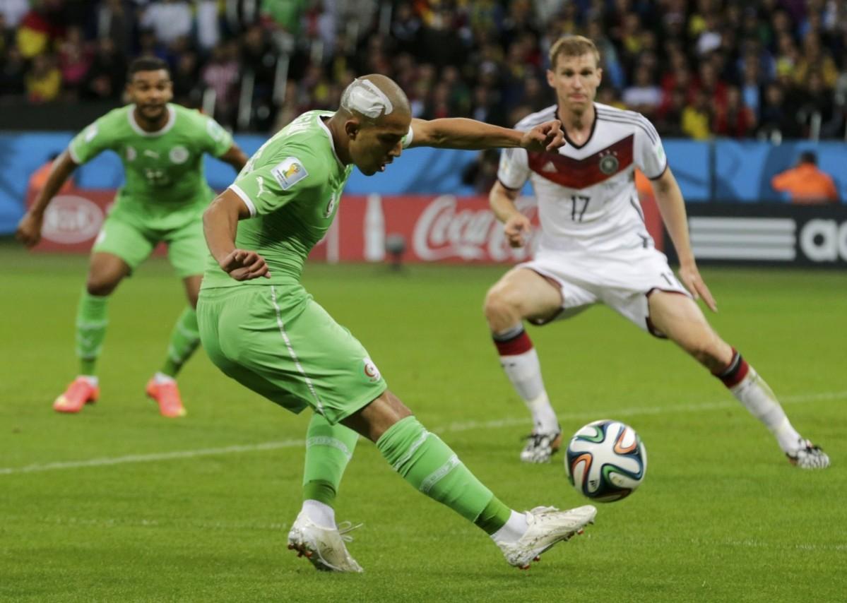 Algeria's Feghouli kicks the ball past Germany's Mertesacker but misses a chance to score a goal, during their 2014 World Cup round of 16 game at the Beira Rio stadium in Porto Alegre Germany vs Algeria