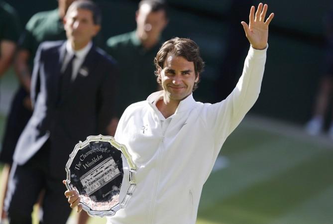 Roger Federer waves while holding the runner-up's trophy after being defeated by Novak Djokovic. Roger Federer