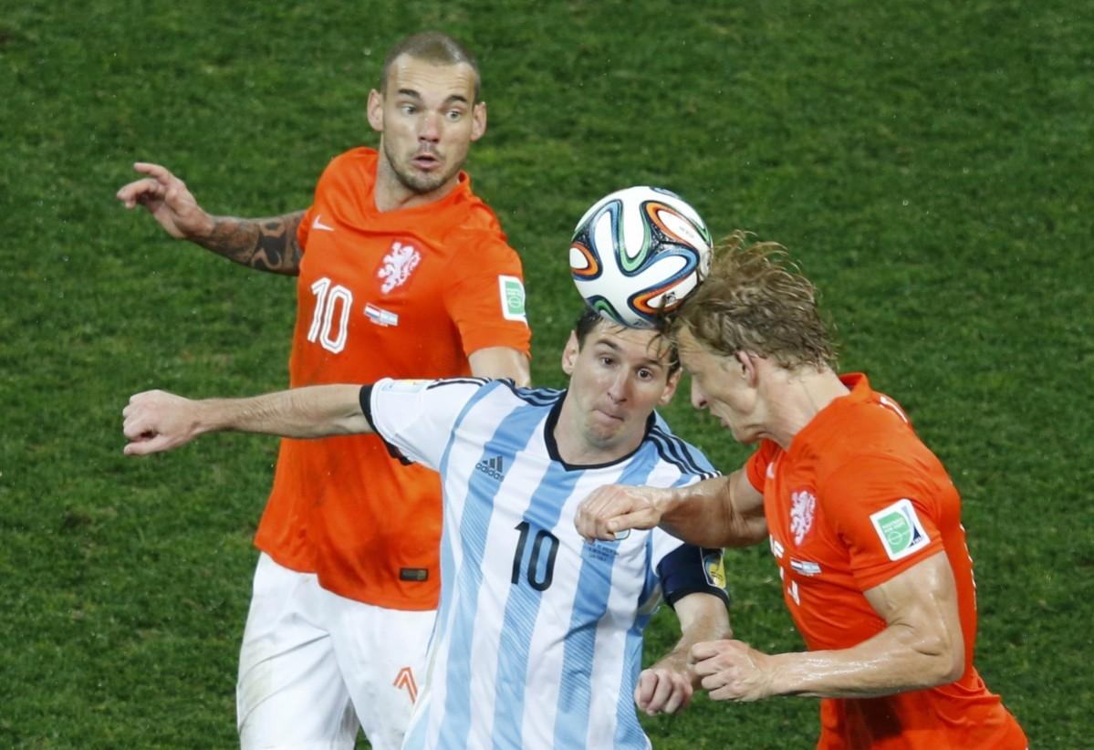 Wesley Sneijder and Dirk Kuyt of the Netherlands fight for the ball against Argentina's Lionel Messi during their 2014 World Cup semi-finals at the Corinthians arena in Sao Paulo Netherlands vs Argentina