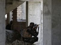 Afghan security personnel take position at the site of an attack, opposite a building where unidentified militants are located at, north of Kabul International Airport in Kabul