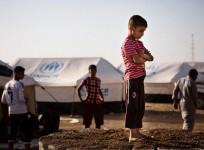 A boy, who fled from the violence in Mosul, stands near tents in a camp for internally displaced people on the outskirts of Arbil in Iraq's Kurdistan region