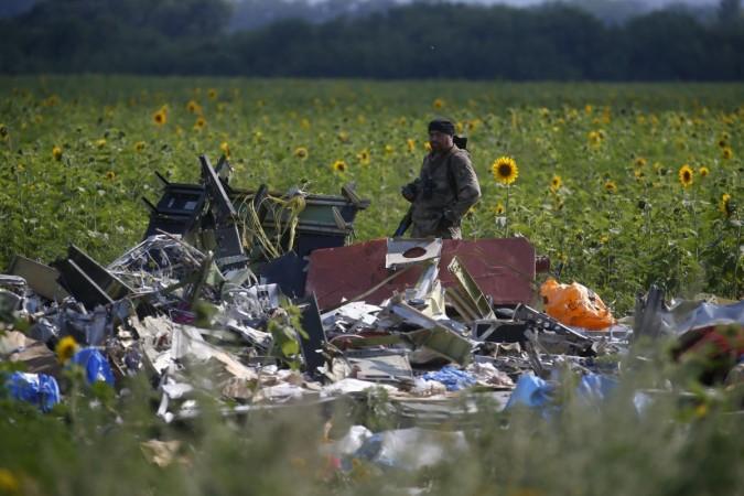 Armed pro-Russian separatist stands guard as OSCE monitors and members of a Malaysian air crash investigation team inspect the crash site of Malaysia Airlines Flight MH17, near the village of Rozsypne, Donetsk region