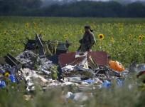 Armed pro-Russian separatist stands guard as OSCE monitors and members of a Malaysian air crash investigation team inspect the crash site of Malaysia Airlines Flight MH17, near the village of Rozsypne, Donetsk region