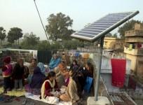 Local women of Dharnai sing on roof of a house where solar panels are installed