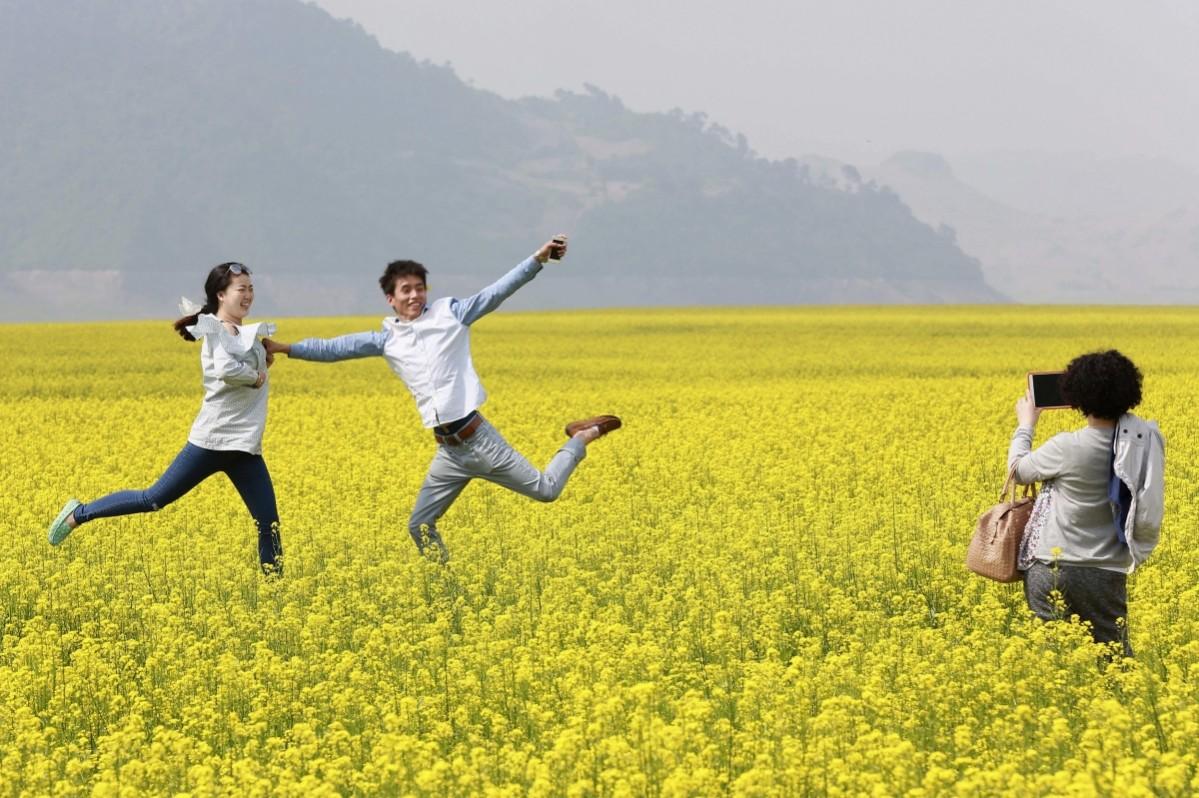 Visitors pose for pictures at a canola flower field in Kuandian county, near China's border with North Korea, Liaoning province, May 30, 2014 Unbelievable Places in the world
