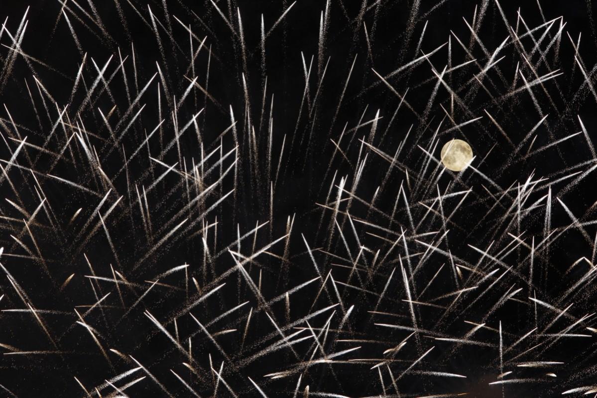 Fireworks streak past in front of the supermoon outside the town of Mosta, celebrating the feast of its patron saint, in central Malta, August 10, 2014. Supermoon
