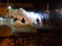 Riot police clear a street with smoke bombs while clashing with demonstrators in Ferguson