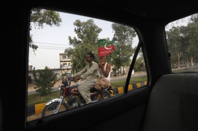 Supporters of cricketer-turned-opposition politician Imran Khan are seen from a window of a car as they ride a motorcycle while carrying a Pakistan Tehreek-e-Insaf (PTI) political party flag, Freedom March
