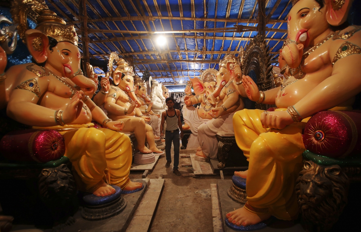 An artisan walks amidst idols of Ganesh