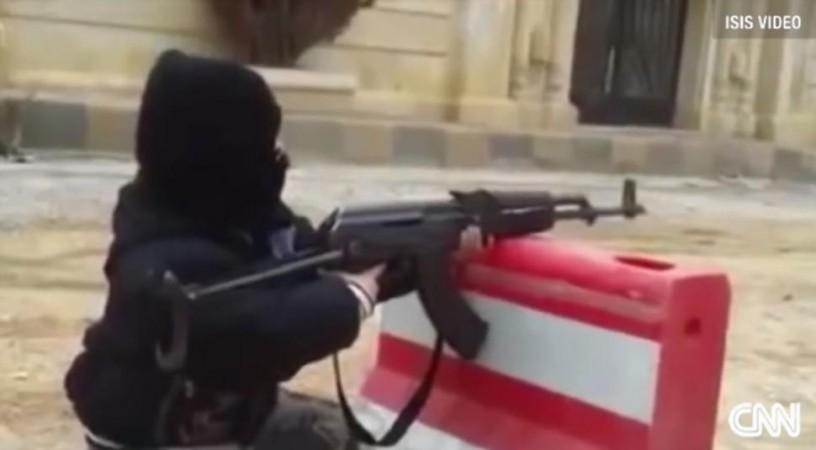 A boy fires an AK-47 at an ISIS training camp. A 10 year old boy fires an AK 47 in an ISIS training camp.