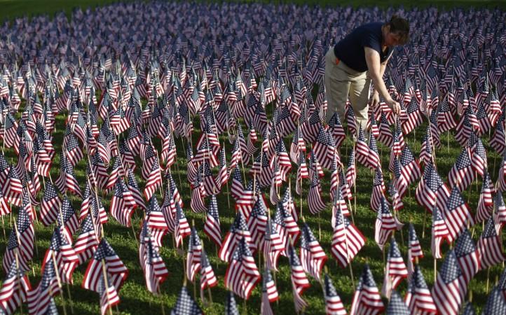 A woman plants some of the 3,000 flags placed in memory of the lives lost in the September 11, 2001 attacks, at a park in Winnetka, Illinois September 10, 2014. September 11