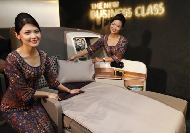 Singapore Airlines Ltd stewardesses pose next to a business class seat during the launch of their new generation of cabin products at Changi Airport in Singapore Business class