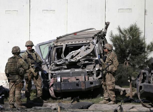 U.S. troops keep watch near a damaged vehicle at the site of suicide attack in Kabul September 16, 2014.