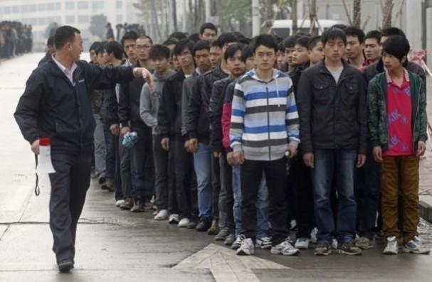 A Foxconn recruiter asks for prospective new workers to line up outside a recruitment center in China A Foxconn recruiter asks for prospective new workers to line up outside a recruitment center in China