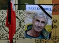 A portrait of mountain guide of Frenchman Herve Gourdel hangs near a French flag outside the town hall in Saint-Martin-Vesubie, September 24, 2014. Algerian militants have released a video that appears to show them beheading Gourdel who was kidnapped on S