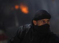 A fighter from the Islamist Syrian rebel group Jabhat al-Nusra is seen in front of a burning vehicle.
