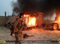 An ISIS fighter looks at a destroyed M113 armored personnel carrier