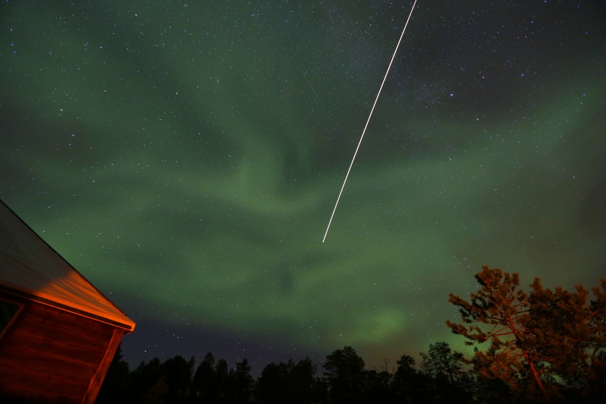 A commercial jetliner flies under Aurora Borealis (Northern Lights) over a mountain camp north of the Arctic Circle, near the village of Mestervik on 2 October 2014. Aurora Borealis (Northern Lights) over a mountain camp north of the Arctic Circle