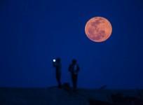 Observers take picture during a blood moon rising in Shanghai.
