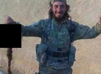 An ISIS militant posing with the head of a captured Kurdish female fighter