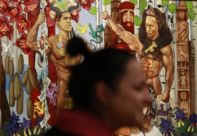 A visitor passes by a painting, displaying Russian Prime Minister Vladimir Putin (R) and U.S. President Barack Obama