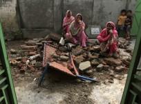 Villagers sit on the debris of their house.
