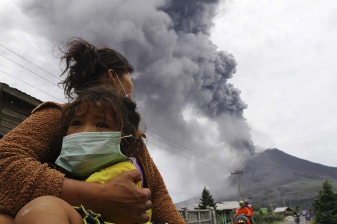 A mother holds her child as Mount Sinabung spews ash and hot lava during an eruption in Perteguhan village in Karo district, Indonesia's north Sumatra province, 17 September 2013. Mount Sinabung volcano erupts
