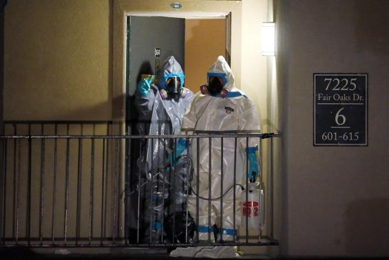 Workers in hazardous material suits step out of an apartment unit where a man diagnosed with the Ebola virus was staying in Dallas, Texas, October 5, 2014.