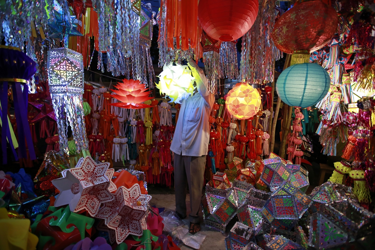 A vendor hangs a lantern for sale at a Diwali market in Mumbai October 20, 2014.