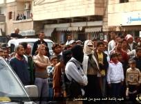 People gather to watch the beheading of three men accused by ISIS of insulting Allah in Raqqa.
