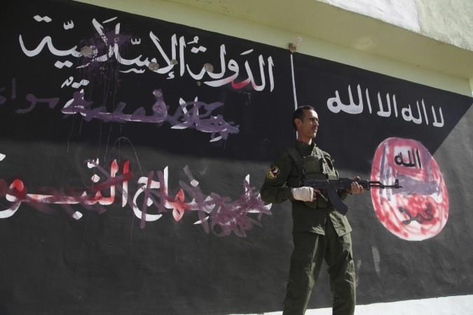 ISIS, Sunni Islamic hardliner jihadists lined up 30 other Sunni men in a town west of Baghdad and shot them dead. (Photo Caption: A Kurdish Peshmerga fighter stands near a wall on which the black flag (R) commonly used by Islamic State militants and other writing have been painted over, in the northern Iraqi town of Zumar, October 26, 2014.) ISIS, Sunni Islamic hardliner jihadists lined up 30 other Sunni men in a town west of Baghdad and shot them dead.