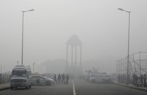 Vendors selling drinks stand beside vehicles near the India Gate war memorial on a smoggy day in New Delhi February 1, 2013. Air Pollution New Delhi